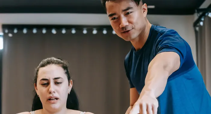 Instrutor orienta mulher em máquina de remo dentro de uma academia
