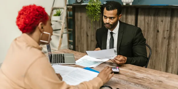Duas pessoas sentadas à mesa de escritório analisando documentos e um notebook, cena que ilustra a dúvida de quem quer saber se preciso de contador para abrir empresa