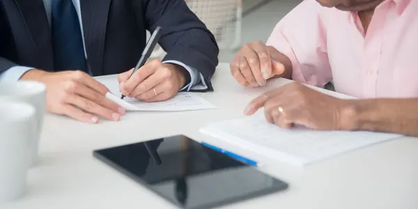 Dois sócios assinando o acordo de sócios sobre a mesa de reunião do escritório