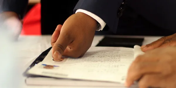 Mão de um empresário apondo a impressão digital em um documento