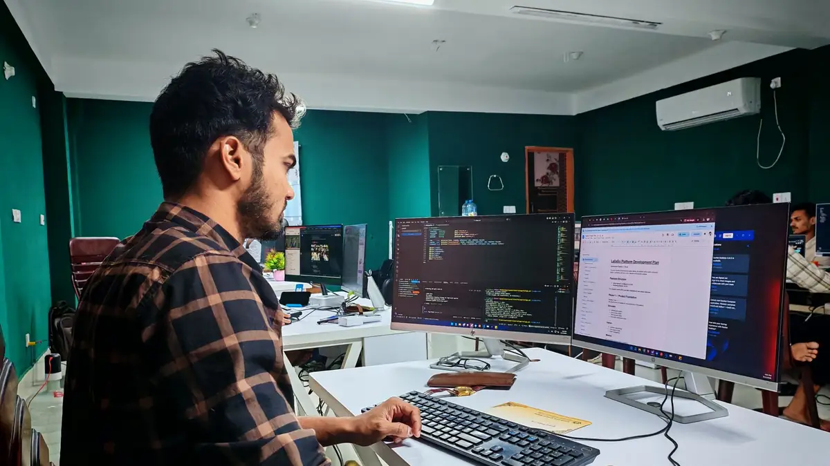 Desenvolvedor trabalhando em dois monitores, com código em uma tela e documentação na outra