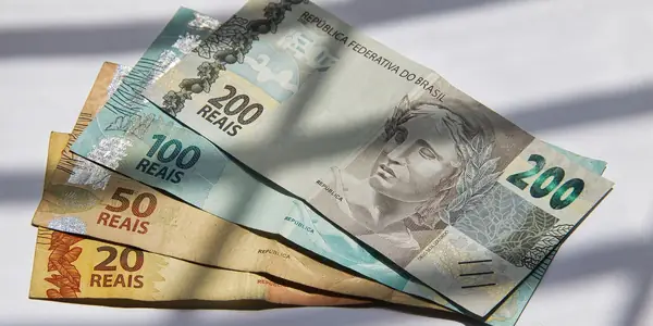 Notas de 20, 50, 100 e 200 reais sobre a mesa, representando o capital social declarado na abertura da empresa