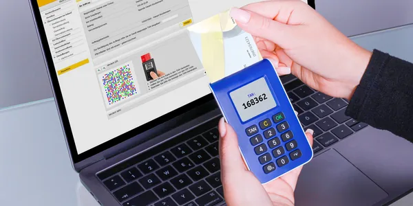 Mãos usando um gerador de código ao lado de um notebook para autenticação segura