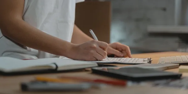 Close de uma pessoa escrevendo em uma prancheta sobre a mesa do escritório