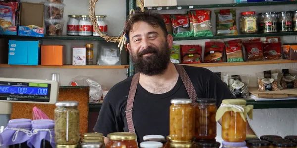 Comerciante atrás das prateleiras de conservas artesanais da sua loja