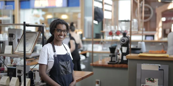 Barista sorrindo atrás do balcão de uma cafeteria