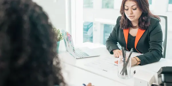 Duas pessoas sentadas à mesa de um escritório analisando documentos durante uma reunião, cena que ilustra as perguntas para contratar contador