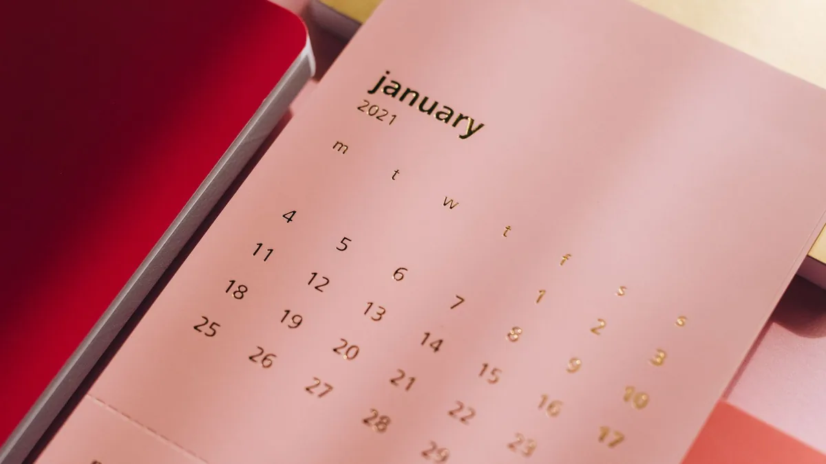 Calendário de mesa aberto sobre uma composição de cadernos coloridos