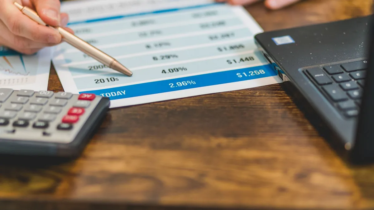 Mão apontando com um lápis os números de um relatório financeiro impresso
