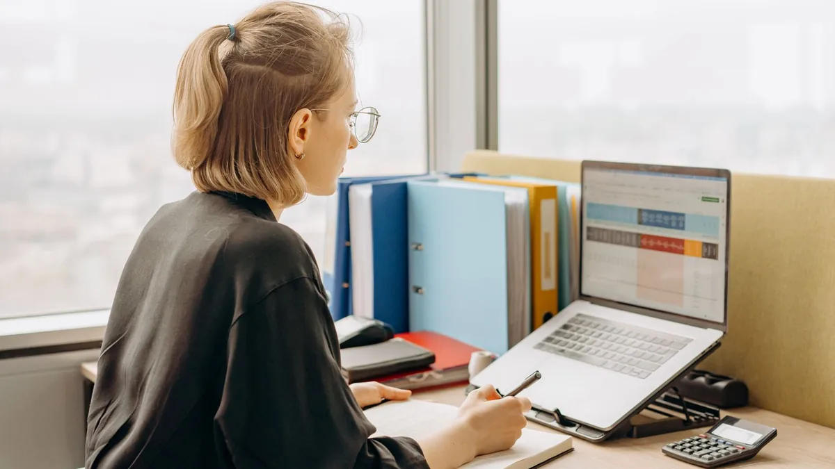 Profissional trabalhando em uma planilha no notebook em uma mesa de escritório
