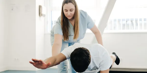 Fisioterapeuta orientando um paciente durante um exercício de alongamento na clínica