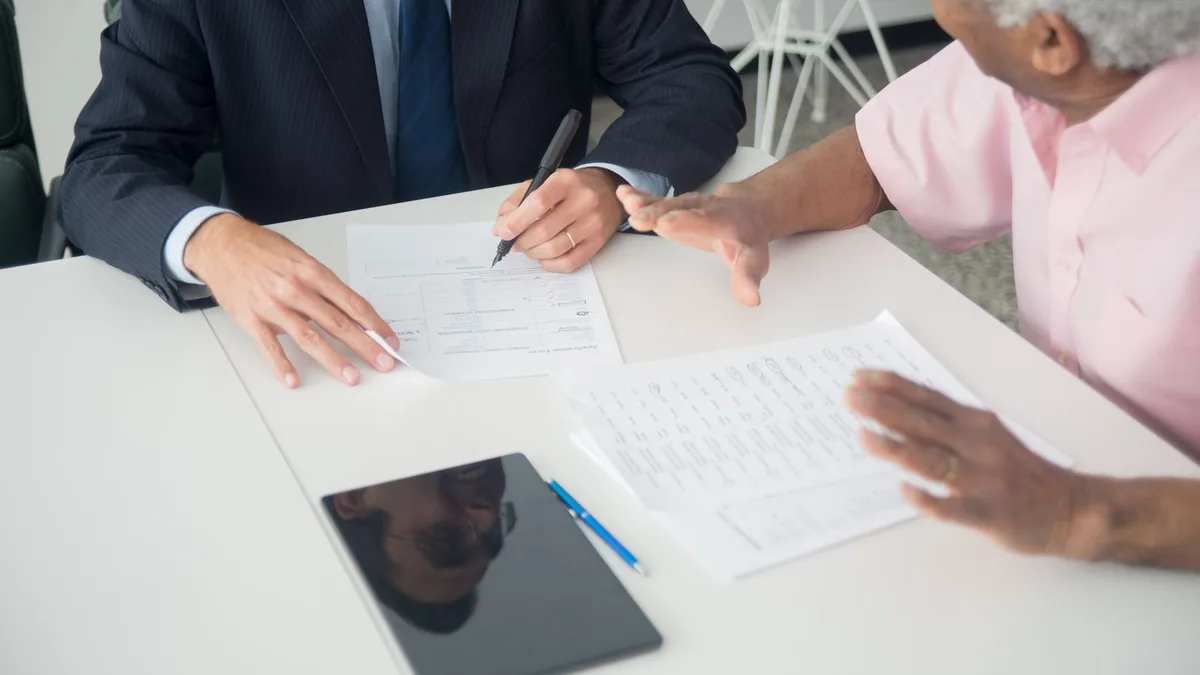Profissional explicando um documento para uma cliente sentada do outro lado da mesa