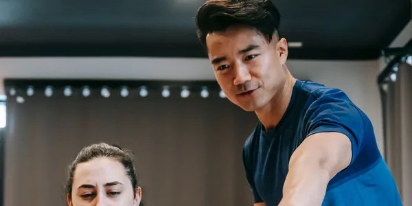 Instrutor orientando uma aluna durante o treino em um aparelho da academia