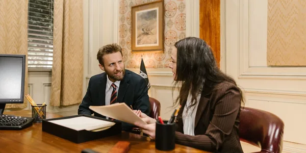 Advogado e cliente conversando sobre documentos à mesa de um escritório
