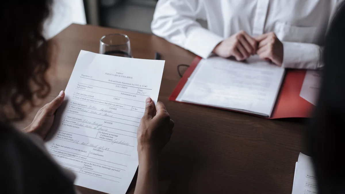 Duas pessoas revisando um contrato impresso sobre a mesa de reunião