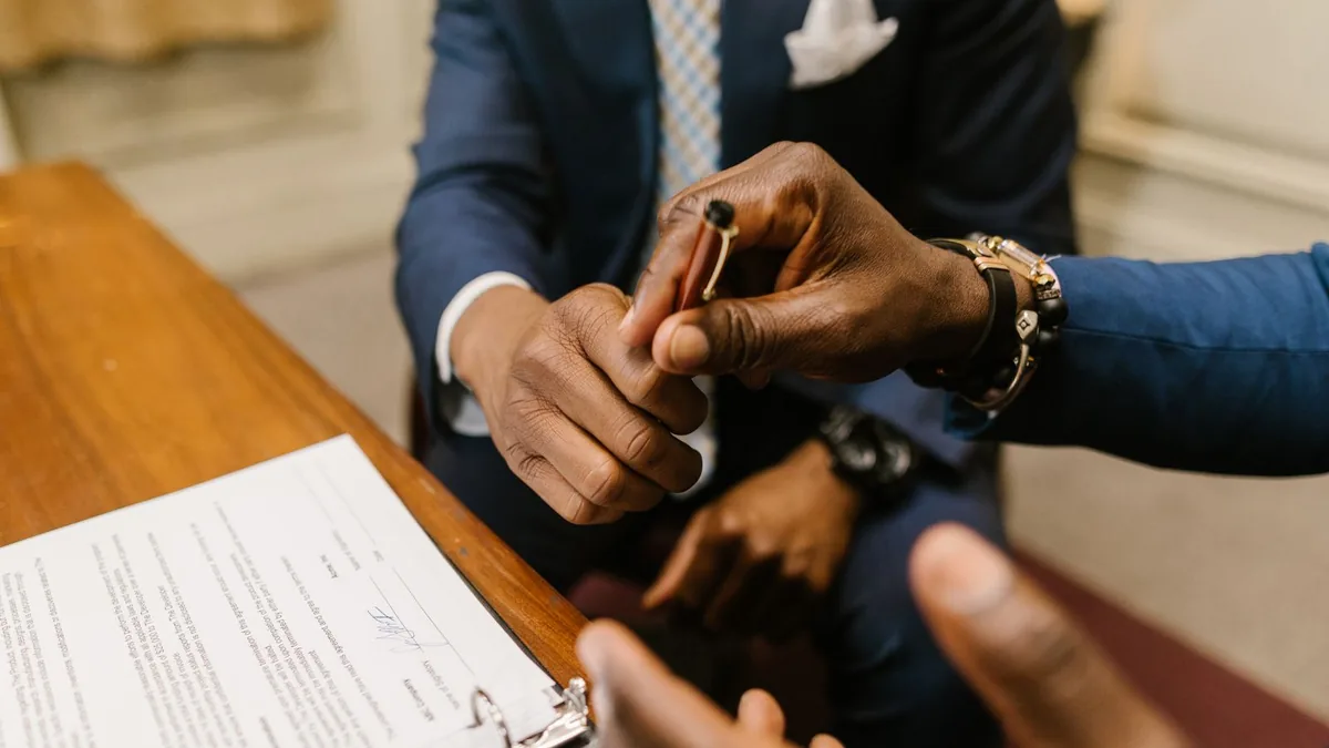 Dois profissionais fechando um acordo com o contrato e a caneta sobre a mesa