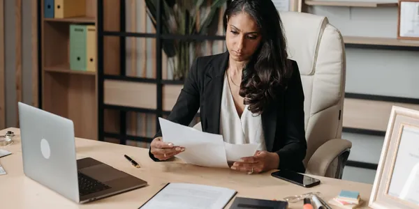 Empresária sentada à mesa com notebook e documentos, organizando papéis para entender como regularizar empresa com pendências no fisco
