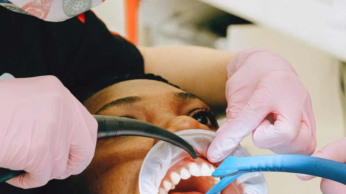 Dentista com luvas e máscara atendendo um paciente na cadeira odontológica