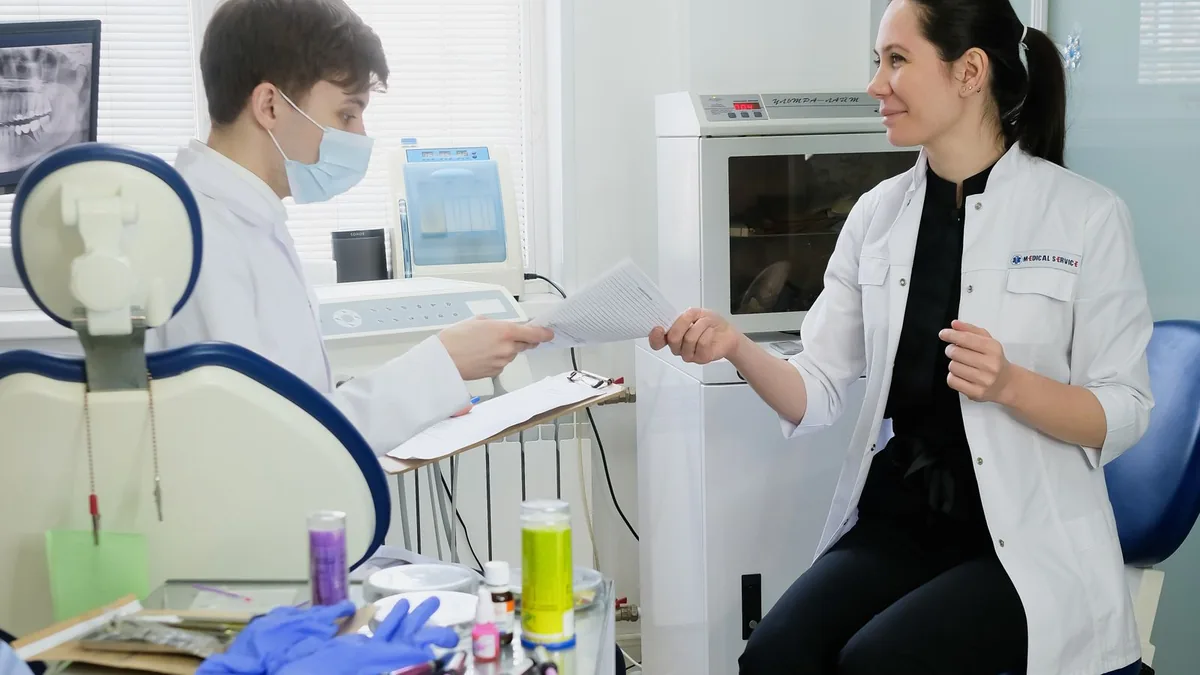 Dentista revisando documentos e anotações em uma mesa ao lado do computador