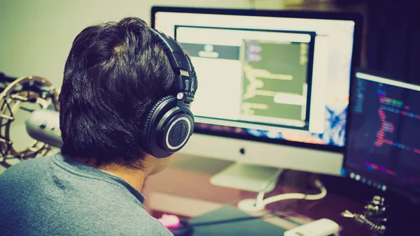 Desenvolvedor programando em frente a dois monitores