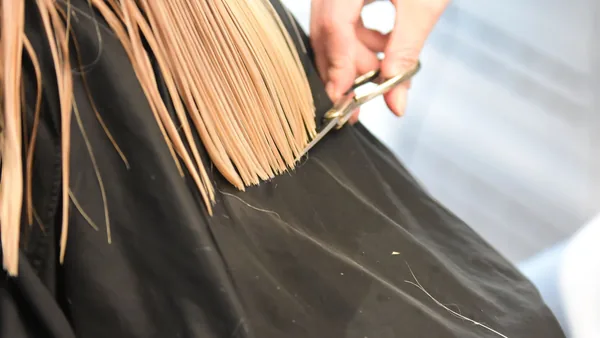 Cabeleireiro cortando o cabelo de uma cliente no salão