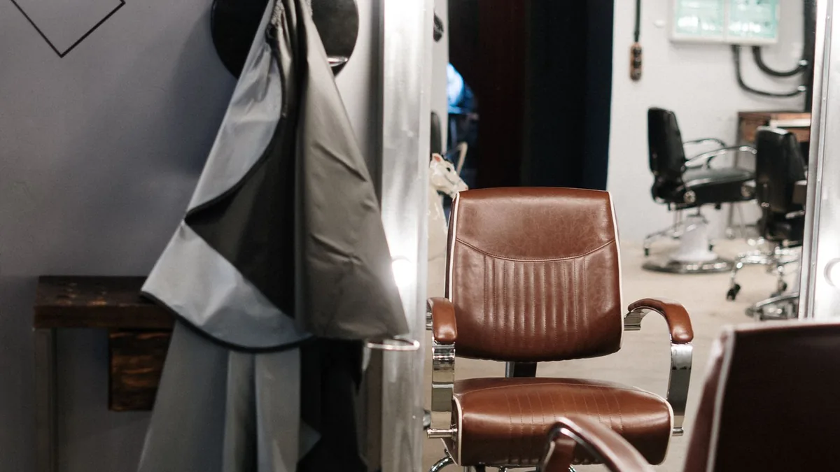 Cabeleireiro finalizando um corte em uma cliente sentada na cadeira do salão