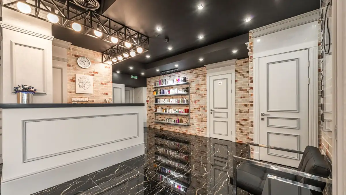Barbeiro atendendo um cliente em uma barbearia com espelhos e iluminação quente
