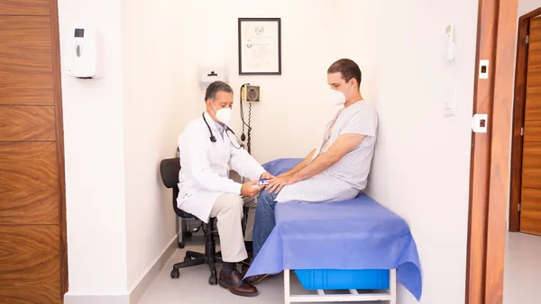 Médico atendendo uma paciente sentada no consultório