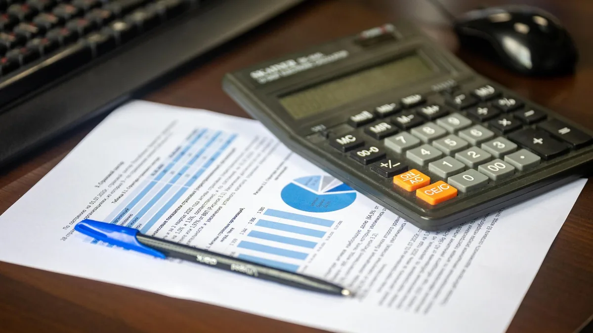 Calculadora, caneta e planilhas impressas sobre uma mesa de escritório