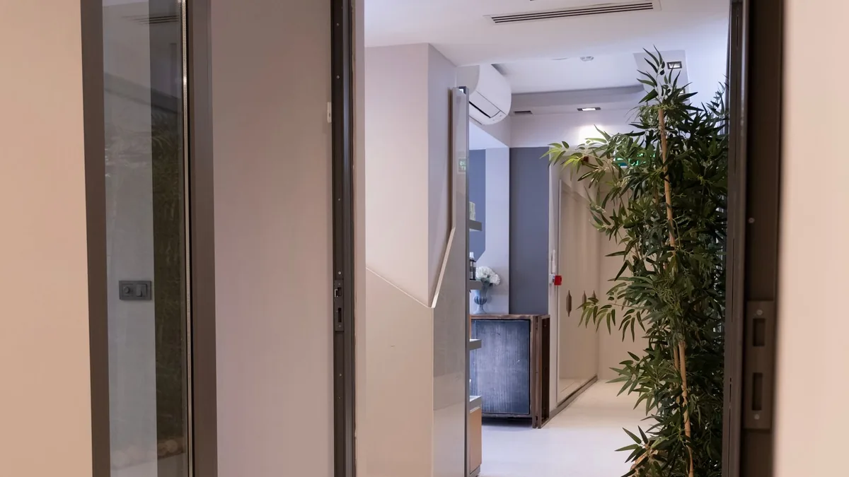 Consultório pequeno com poltronas, mesa e plantas, pronto para atendimento