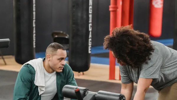 Personal trainer acompanhando o treino de um aluno na academia