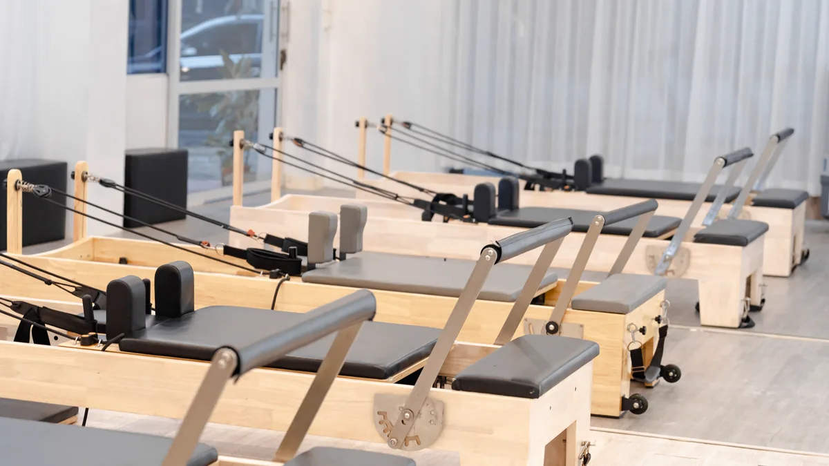 Personal trainer orientando um aluno em um exercício com halteres na academia