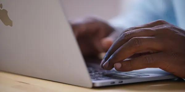 Mãos digitando no notebook para fazer a consulta de nome empresarial antes de registrar a empresa