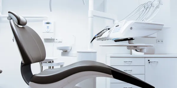 Cadeira e equipamento de consult&oacute;rio odontol&oacute;gico em uma sala clara