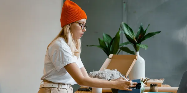 Lojista embalando um pedido em uma caixa sobre a mesa