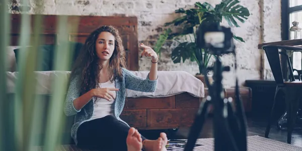 Criadora de conte&uacute;do gravando um v&iacute;deo com c&acirc;mera em trip&eacute; dentro de casa