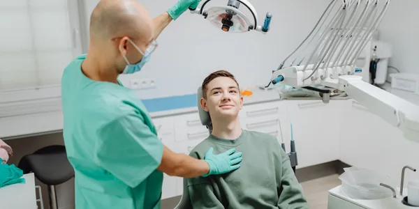 Dentista atendendo um paciente na cadeira de um consultório odontológico