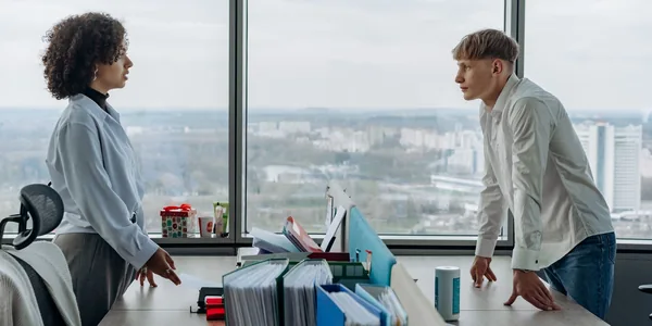 Dois colegas conversando em um escritório com vista para a cidade