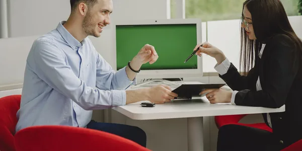 Dois profissionais em reunião na mesa de um escritório moderno