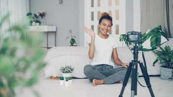 Criadora de conteúdo gravando vídeo com câmera e tripé em casa