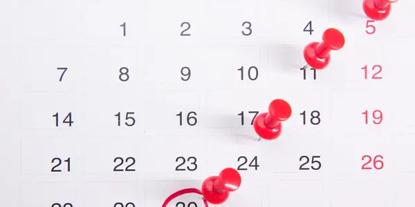 Calendário com alfinetes vermelhos marcando datas importantes do cronograma da Reforma Tributária