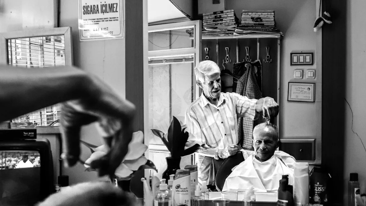 Barbeiro atendendo cliente na cadeira da barbearia