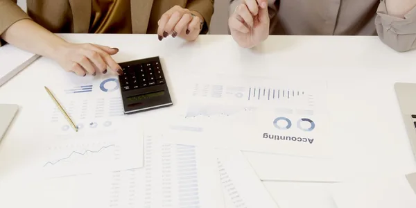 Dois profissionais conferindo documentos financeiros com uma calculadora