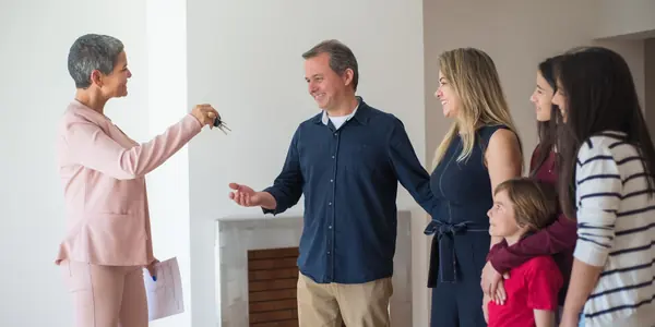 Família de três gerações recebendo as chaves de um imóvel, representando o patrimônio organizado em holding familiar