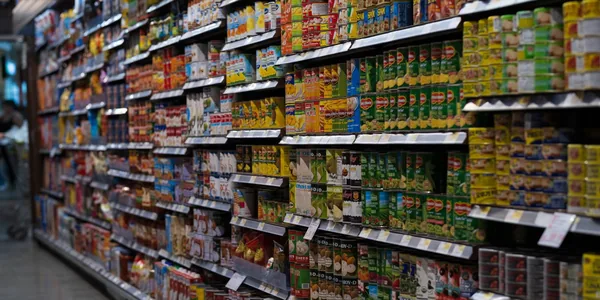 Corredor de supermercado com prateleiras de produtos, ilustrando os itens atingidos pelo Imposto Seletivo