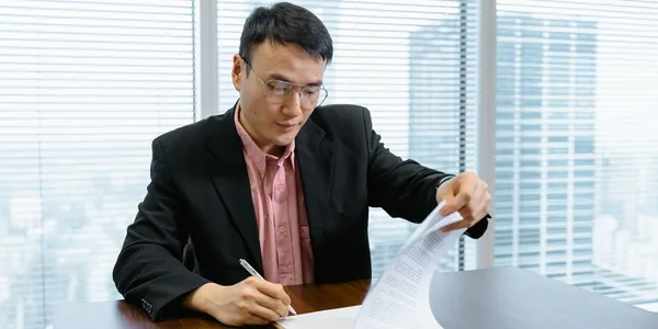 Empresário de terno assinando papéis na mesa do escritório