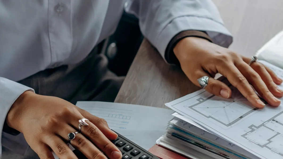 Duas pessoas conferindo documentos com uma calculadora sobre a mesa