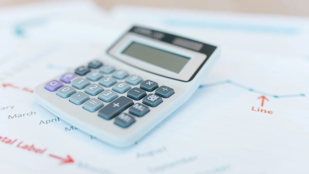 Calculadora branca apoiada sobre um gráfico impresso com os meses do ano