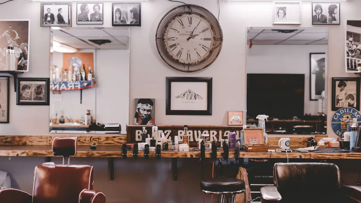 Interior de barbearia com cadeiras de couro, bancada de madeira e quadros na parede
