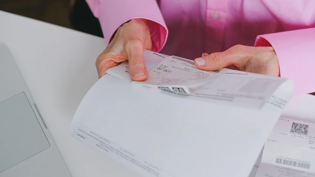 Business person handling paper receipts, meticulously organized.